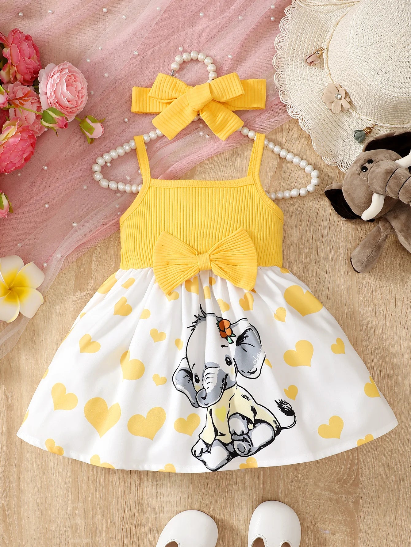 Abito estivo alla moda per bambina con grazioso cuoricino e bretelle a forma di elefantino dei cartoni animati.