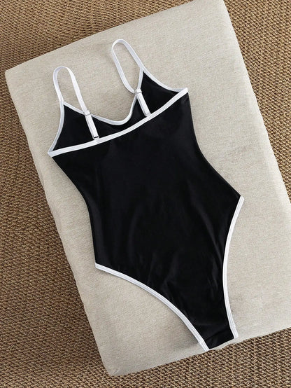 Costume intero da donna nero con finiture bianche, scollatura sulla schiena, taglio alto e sgambato, ideale per l'estate e le vacanze al mare.